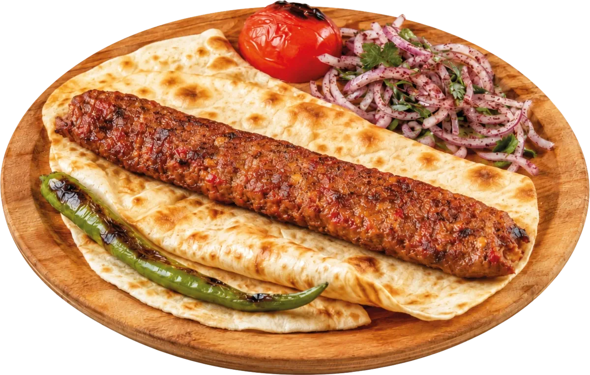 Lavaş üzerinde Adana kebap, közlenmiş domates ve sumaklı soğanla